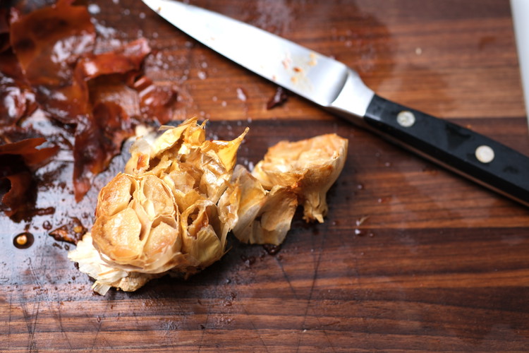Image of Carefully cut the top off of the roasted garlic head.  You are going to squeeze out the roasted garlic in the next step. Discard the skins.