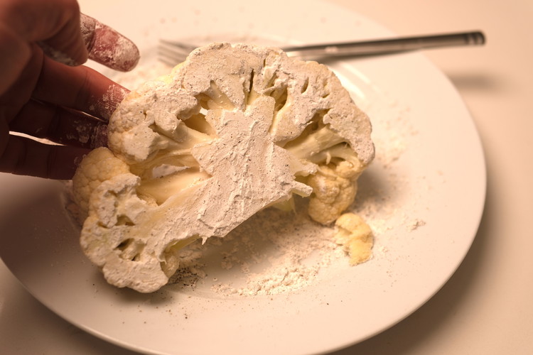 Image of Mix corn starch, salt, black pepper in a plate and dust the cauliflower steak with it.  Shake off the excess
