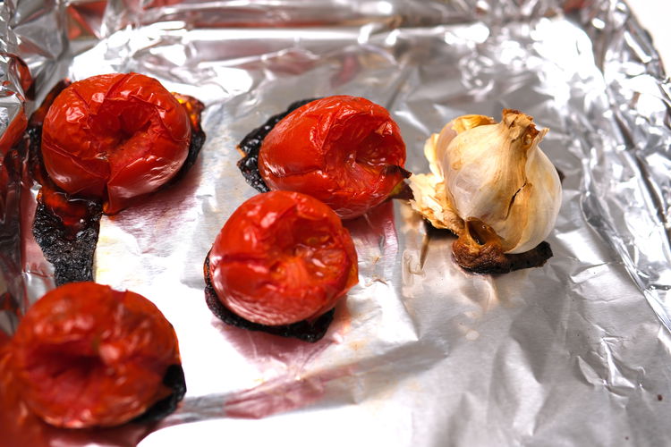 Image of Place tomatoes and garlic on foil on a baking sheet...