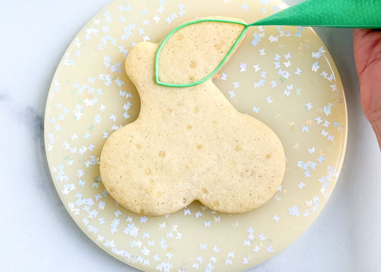 Image of Using the green outline consistency icing, outline the leaf section as shown in the photo. Then, outline the stem section as shown in the photo. 