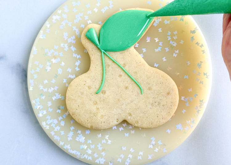 Image of Fill in the shape of the leaf with the light green flood consistency icing.  Use your scribe tool or a toothpick to smooth out the icing and pop any air bubbles that come up. 