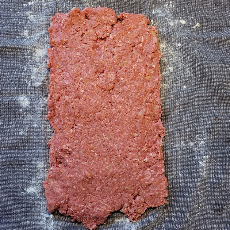 Image of  Ein Küchentuch leicht mit Mehl bestäuben. Hackfleisch darauf geben und ca. 1 cm dick auswallen