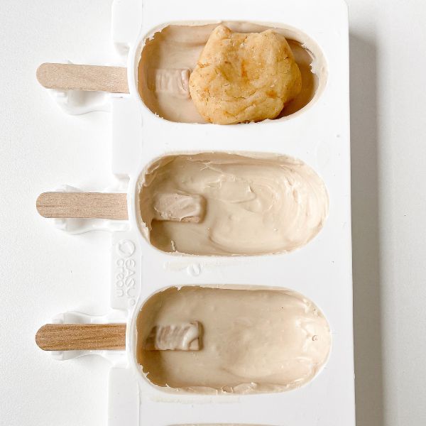Image of Kuchenteig in die Formen füllen und mit Kuvertüre verschließen. Wieder ins Gefrierfach für zehn Minuten. Etwas Kuvertüre zum Verzieren aufbewahren. 
