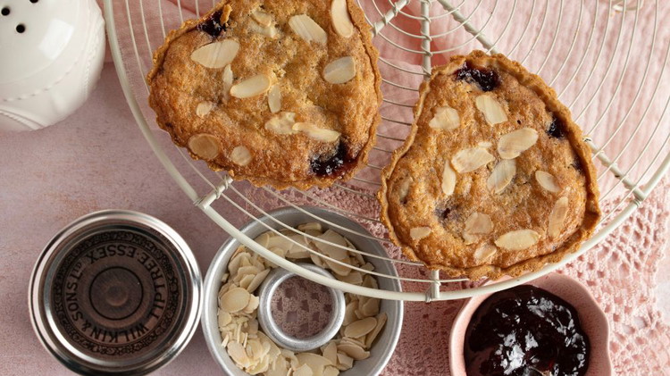 Image of Spread the Tiptree Raspberry Seedless Conserve over the cooked pastry shell using a palette knife. Add the frangipane on top and spread nearly to the edges, to allow for expansion, trying not to mix the frangipane with the jam. Scatter...