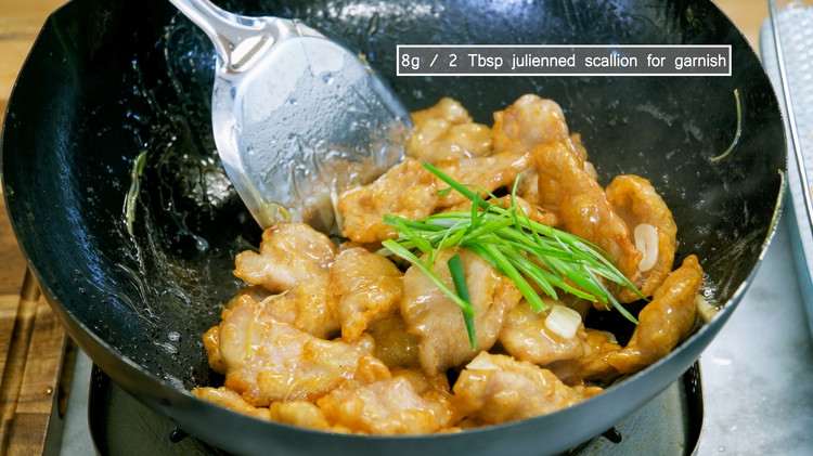 Image of Add the fried crispy pork and toss thoroughly. Garnish with the julienned scallions and serve as an appetizer.