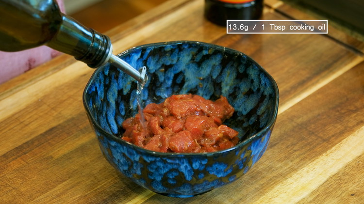 Image of Drizzle in 1 Tbsp of cooking oil and mix to coat the beef nicely. This helps to separate the slices so they don’t stick together while deep frying.