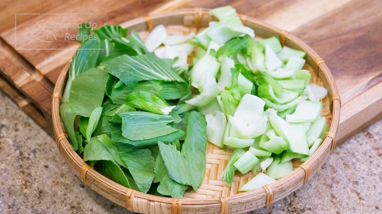 Image of Wash the baby bok choy thoroughly, then tear the leaves off. Stack the leaves and cut them into bite-size pieces. Separate the stems and the leaves because they take different amounts of time to cook.