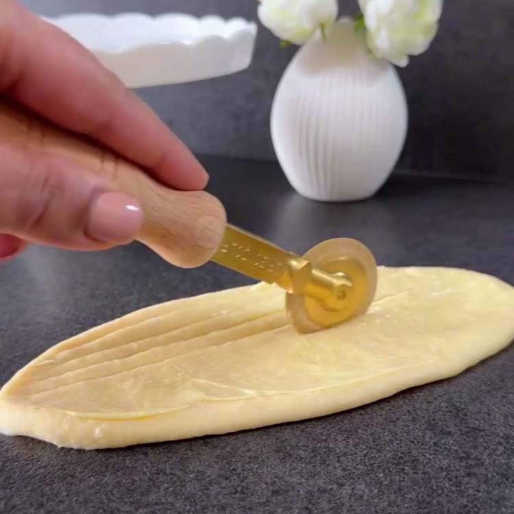 Image of 4. Pinta cada pieza de masa ovalada con la mantequilla blanda infusionada con vainilla. Haz múltiples cortes en el medio de cada óvalo, pero sin llegar a los bordes.