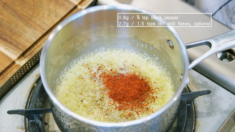 Image of Add 1/3 tsp ground black pepper, and optionally 1.5 tsps red chili flakes. Stir until the butter turns into a bright red color. Remove the saucepan from the stove.