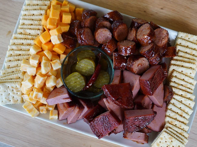 BBQ charcuterie board with cheese, crackers, sausage, pickles