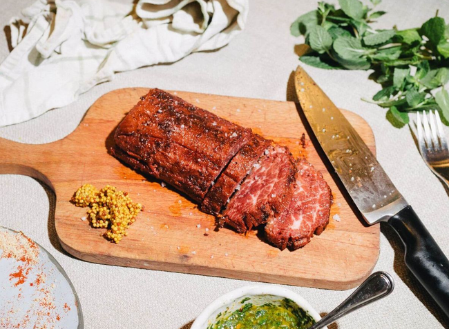 Sliced plant-based flank with vibrant green chermoula sauce