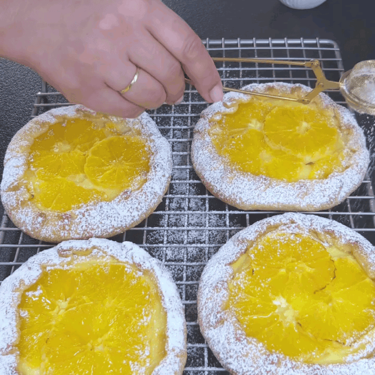 Image of Remove the Orange Galettes from the oven and let them cool slightly. Sprinkle the edges with powdered sugar. Optional: Brush the Galettes with maple syrup for some extra shining.