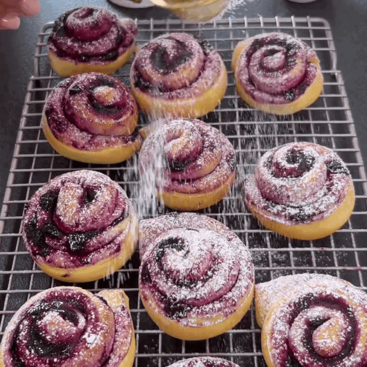 Image of Die Blaubeerbrötchen mit Puderzucker bestäuben für den letzten Schliff.