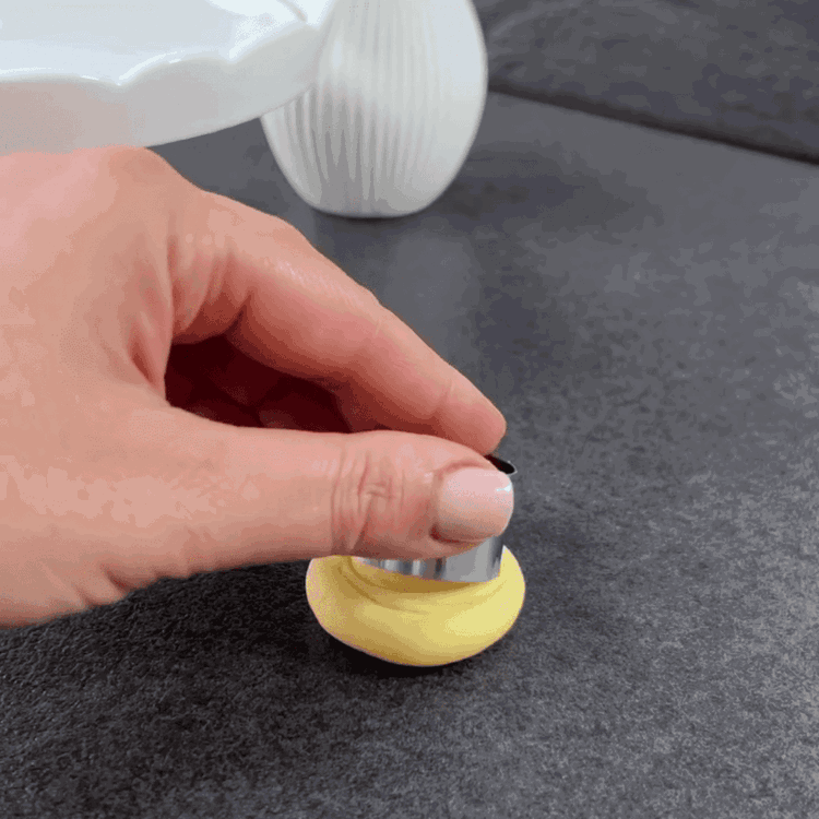 Image of Premi delicatamente ogni pallina e utilizza un tagliabiscotti rotondo per creare delle indentazioni a forma di mezza luna dall'esterno verso l'interno, formando una rosa.