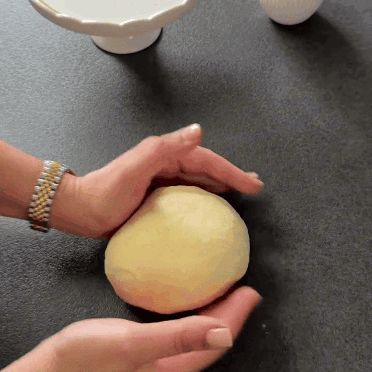 Image of Pétrissez à nouveau la pâte sur une surface farinée. Divisez-la en deux parts égales et formez des boules.