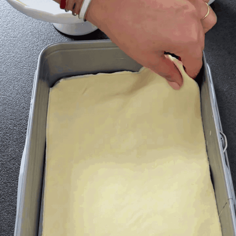 Image of Stendi un foglio di pasta sfoglia e posizionalo nella teglia preparata. Rimuovi eventuali bordi in eccesso