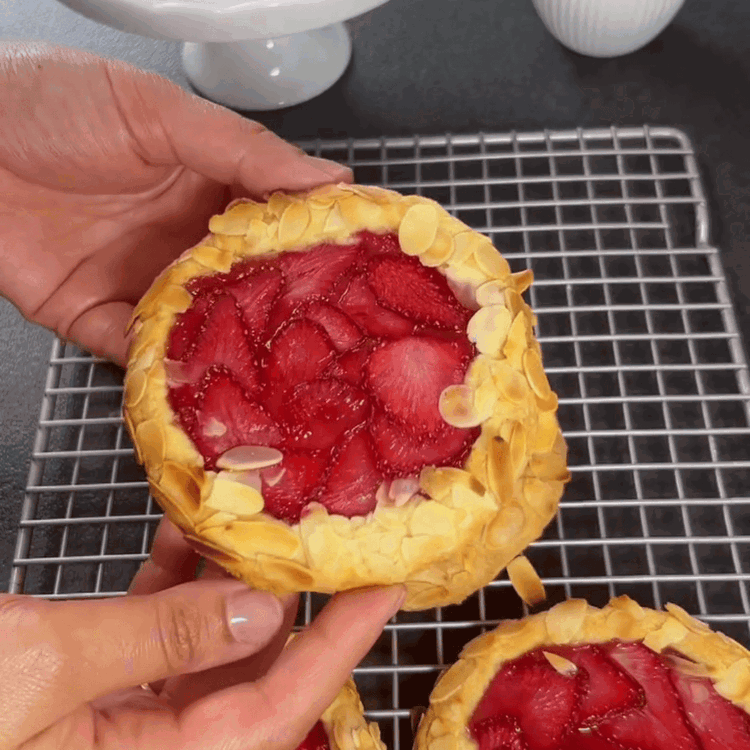 Image of Die Ränder der Galettes vorsichtig einklappen und verschließen. Die Ränder mit etwas Wasser bestreichen und mit Mandelblättchen bestreuen, um sie zu versiegeln.