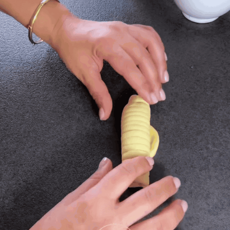Image of Jede Kugel zu einer ovalen Form ausrollen. 1 Esslöffel Vanillepudding in den unteren Teil des Teigs geben, dann Querschnitte machen und oben etwas Platz lassen.