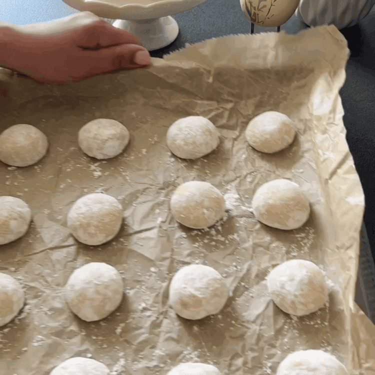 Image of Walnussgroße Bällchen aus dem Teig formen und vollständig in Puderzucker wälzen. Die beschichteten Bällchen auf ein mit Backpapier ausgelegtes Backblech legen und genügend Abstand lassen.