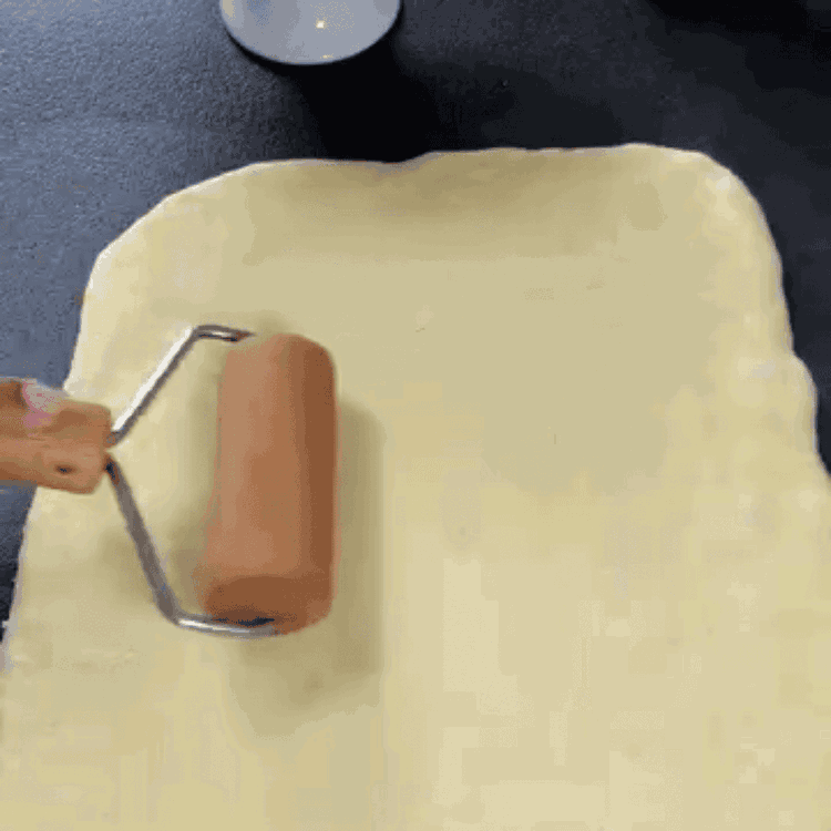 Image of Den gegangenen Teig auf einer leicht bemehlten Fläche zu einem Rechteck (ca. 0,5 cm dick) ausrollen. Die Haselnussfüllung gleichmäßig auf der gesamten Fläche verteilen. Den Teig zu einer Rolle formen und in gleichmäßige Scheiben (ca. 8-10 Stück) schneiden. Jede Scheibe...