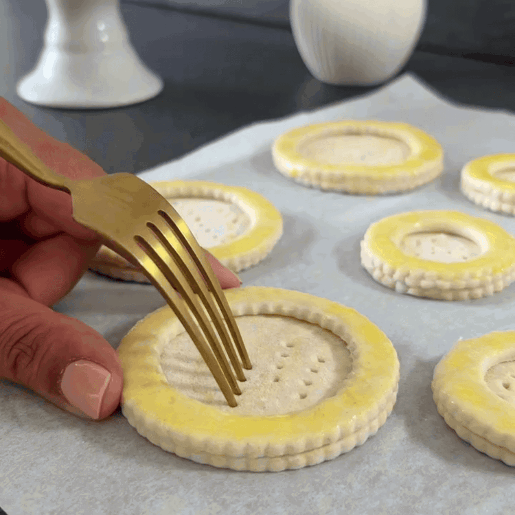 Image of Legen Sie die vorbereiteten Ringe auf ein mit Backpapier ausgelegtes Blech. Stechen Sie die Mitte der Ringe ein paar Mal mit einer Gabel ein, um zu verhindern, dass sie aufgehen. Backen Sie im vorgeheizten Ofen etwa 20 Minuten lang, bis...