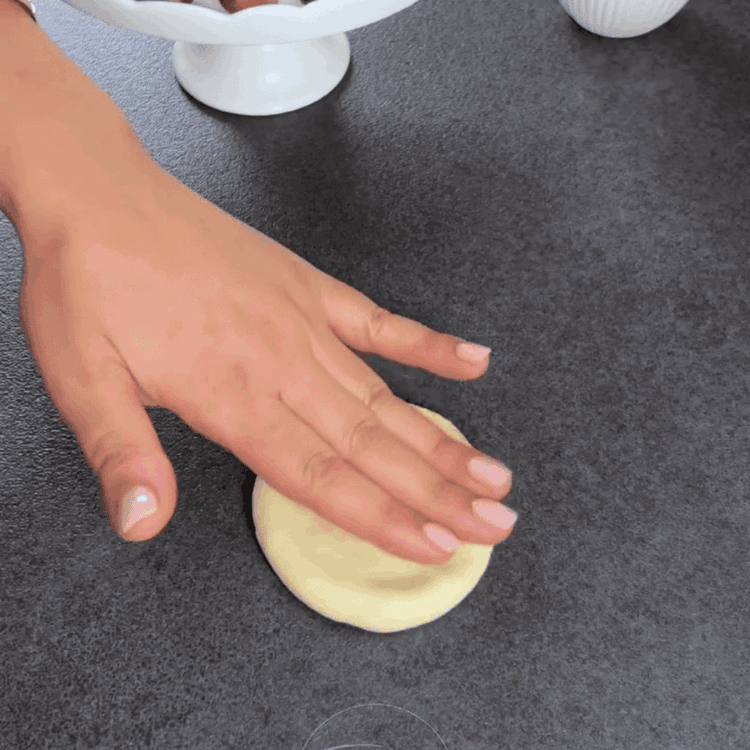 Image of Mit einem Nudelholz oder der Handfläche die verschlossene Seite flachdrücken und auf der Hälfte der Bälle Einschnitte machen, um sie in Crescents zu formen.