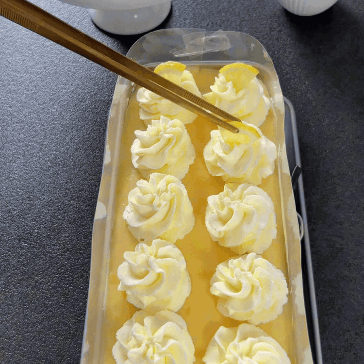 Image of Bate la crema con el azúcar en polvo y el extracto de vainilla hasta que se formen picos firmes. Decora la crema batida sobre el pudín y adorna con pequeños trozos de limón.