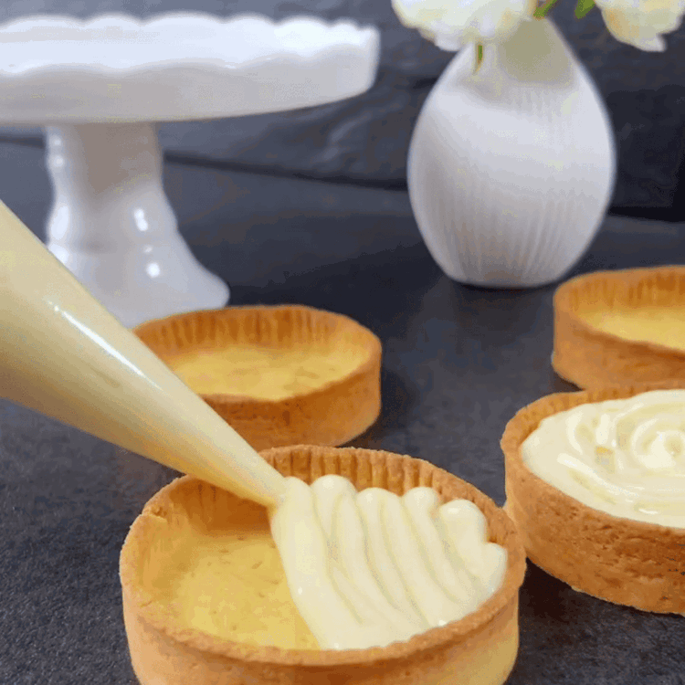 Image of Verwenden Sie einen Handmixer oder einen Schneebesen, um die abgekühlte Kokoscreme glatt zu schlagen. Füllen Sie die Tartelettes mit der Kokoscreme und verteilen Sie sie gleichmäßig.