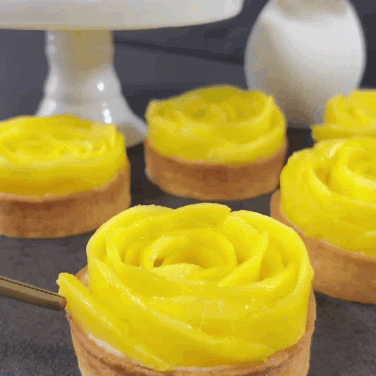 Image of Formen Sie die dünnen Mangoscheiben zu Rosen und legen Sie eine auf jede Tartelette.