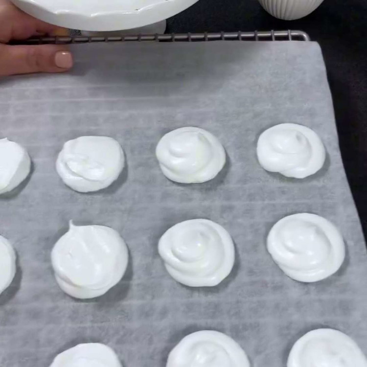 Image of Faites cuire dans le four préchauffé pendant 1,5 à 2 heures, jusqu'à ce que les meringues soient sèches et se détachent facilement du papier sulfurisé. Laissez les meringues refroidir complètement sur une grille.
