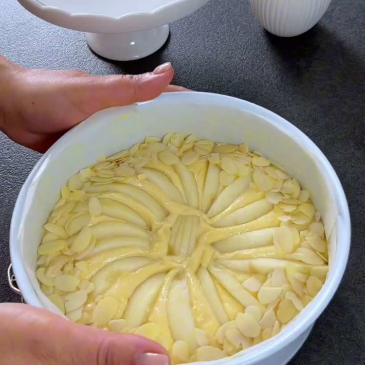 Image of Legen Sie die Birnenscheiben auf den Teig und drücken Sie sie vorsichtig hinein. Dekorieren Sie die Seiten mit Mandelblättchen.