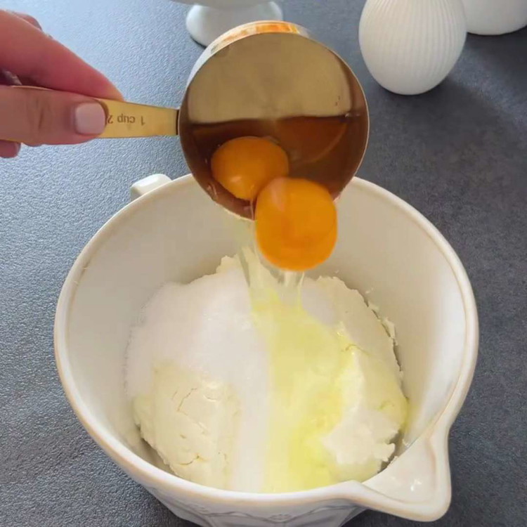 Image of Per il ripieno: A mano, unisci quark o formaggio cremoso, uova e zucchero in una ciotola. Mescola l'amido di mais, l'olio, la panna acida e la panna insieme, aggiungi questo composto al mix di quark e piega delicatamente.