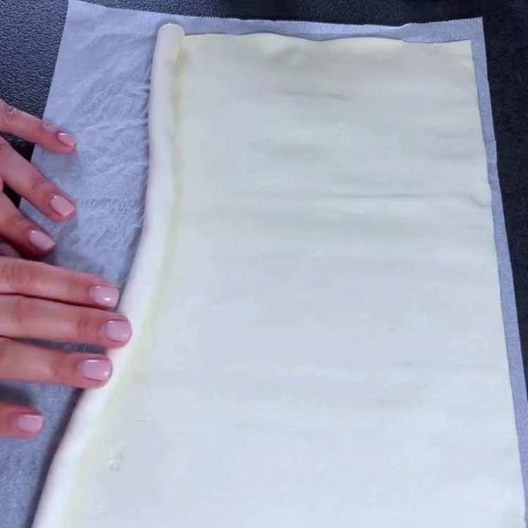Image of Den Blätterteig ausrollen und von der langen Seite her erneut aufrollen, um eine neue Rolle zu formen.