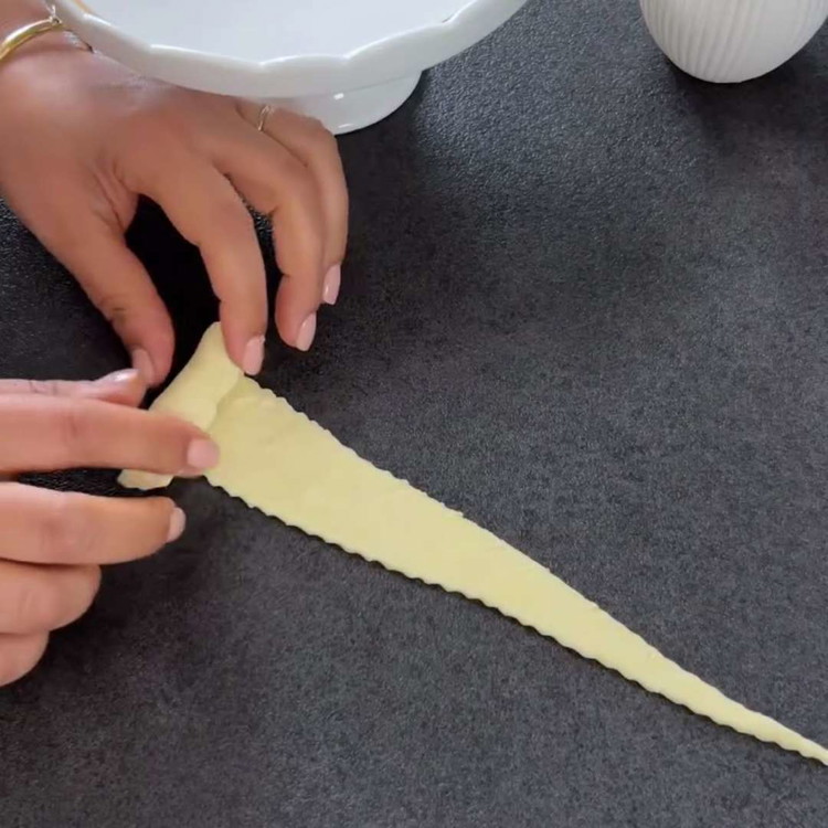Image of لف المثلثات من القاعدة إلى الطرف وضعها على صينية خبز مغطاة بورق الزبدة.