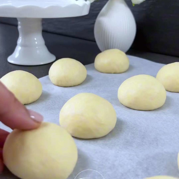 Image of Façonnez la pâte levée en 17 petites boules (50 g chacune) et placez-les sur une plaque de cuisson recouverte de papier sulfurisé. Laissez les boules de pâte lever légèrement.