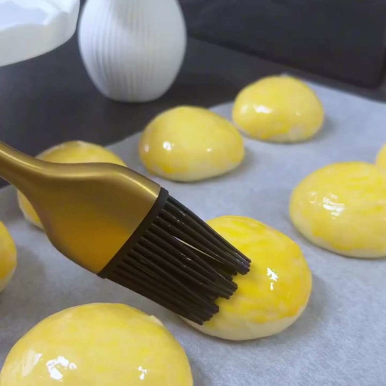 Image of Badigeonnez les boules de pâte avec un mélange de jaune d'œuf et de crème ou de lait.