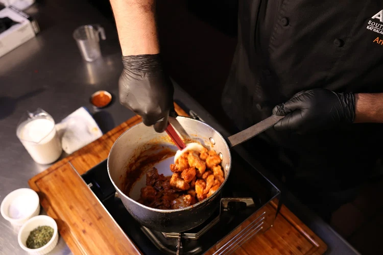 Image of Gently fold the cooked chicken into the sauce, coating each piece evenly.