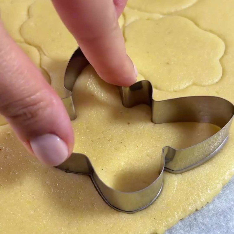 Image of Rol het gekoelde deeg uit op een licht met bloem bestoven oppervlak en snijd vormen uit met koekjesuitsteekvormpjes, de dikte moet 0,5 cm zijn. Tip: Zorg ervoor dat de uitsteekvormpjes koel blijven door het uitgerolde deeg kort te koelen voordat...