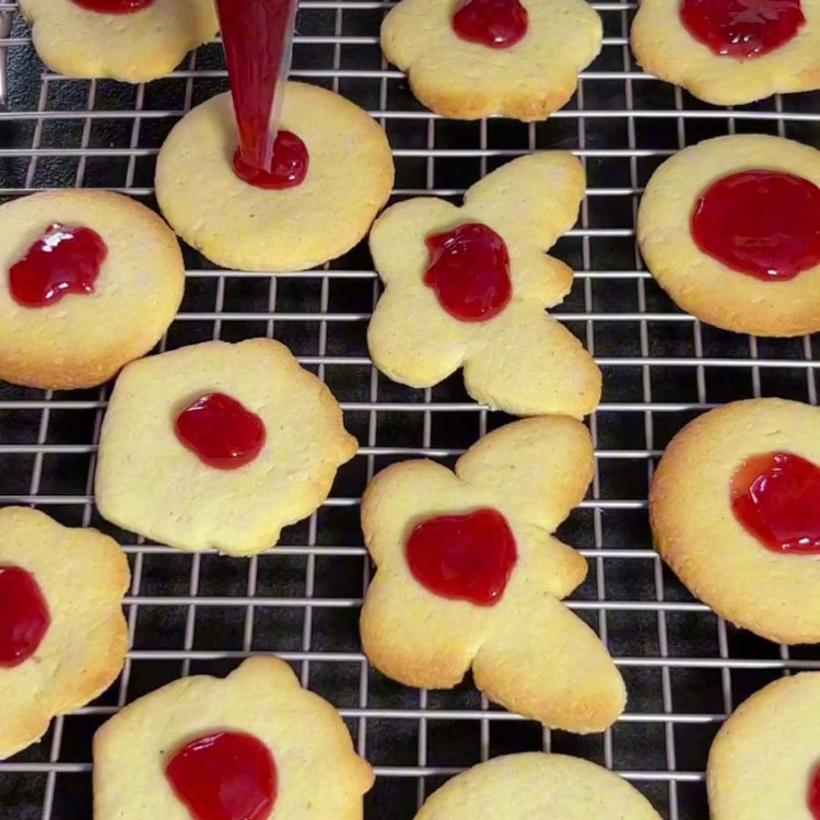 Image of Smeer jam op de koekjes zonder gaten en bestuif de koekjes met gaten met poedersuiker. Combineer de stukken.