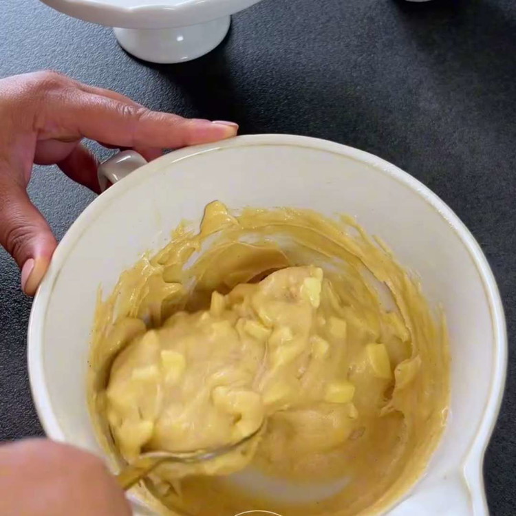 Image of Tillsätt de torra ingredienserna till de blöta ingredienserna och rör försiktigt tills de just har blandats. Vänd ner det tärnade äpplet och de hackade nötterna.