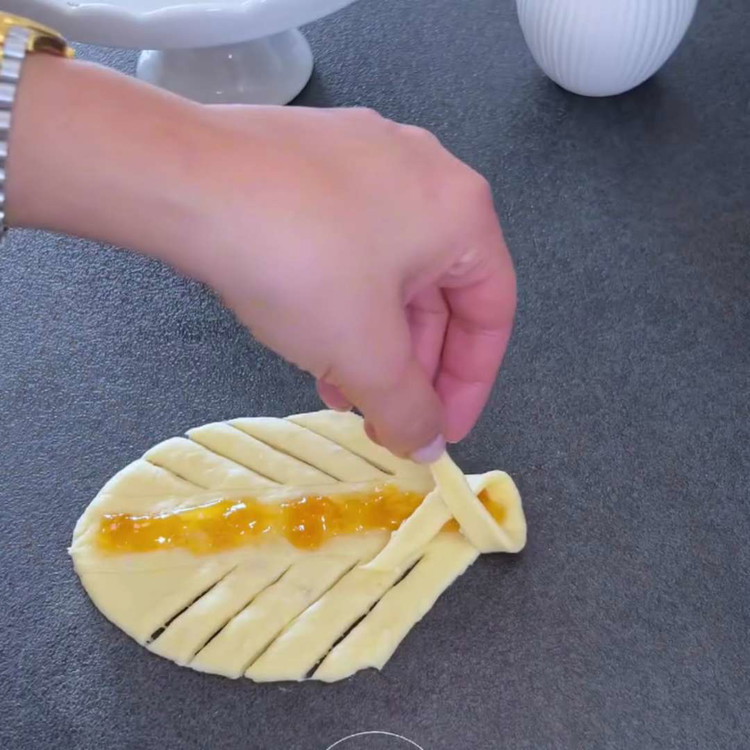 Image of Intreccia alternativamente l'impasto dai lati destro e sinistro. Allenta l'impasto intrecciato e arrotolalo in un tronco. Posiziona i panini su una teglia e lasciali lievitare nuovamente per 30 minuti o fino a quando non aumentano di dimensione.