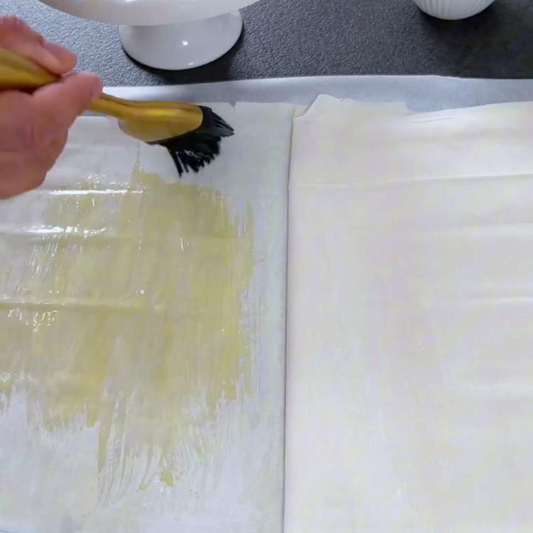 Image of Her bir yufka katmanını eritilmiş tereyağı ile bolca yağlayın ve üst üste yerleştirin.