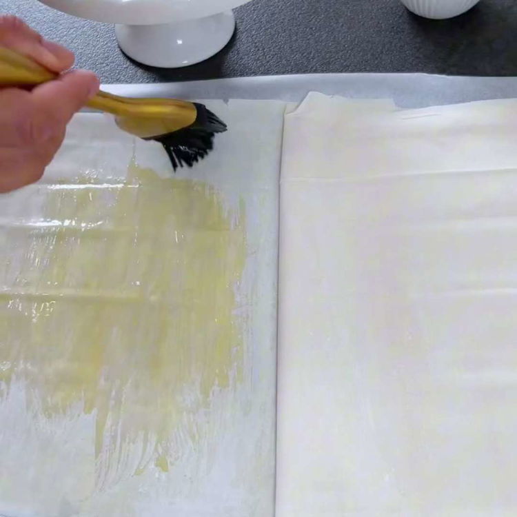 Image of Unta generosamente cada capa de masa filo con mantequilla derretida...