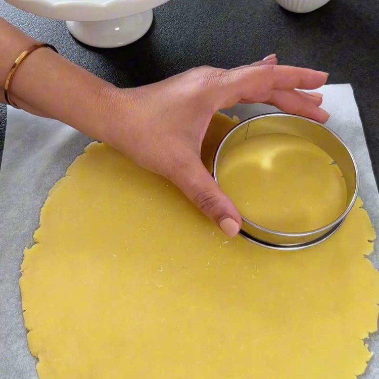 Image of Stendi l'impasto su una superficie infarinata e ritaglia 6 cerchi di dimensioni uguali (circa 12 cm di diametro). Posiziona i cerchi di impasto sulla teglia preparata.