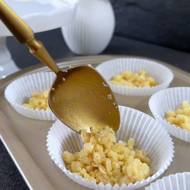 Image of Legen Sie die Erdbeerscheiben in die Mitte jedes Förmchens und bedecken Sie sie mit einer weiteren Schicht Streusel.