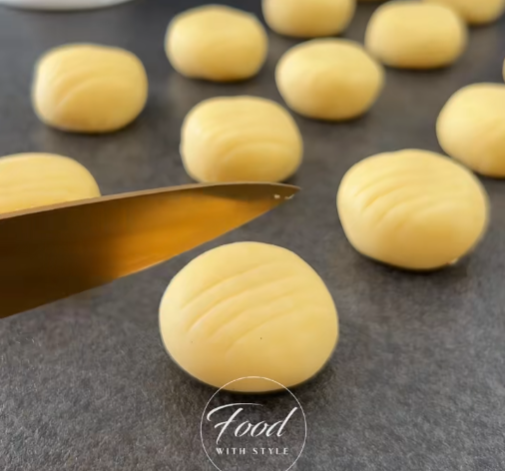 Image of Aplana suavemente cada bola de masa con la palma de tu mano para crear una forma redonda de galleta.