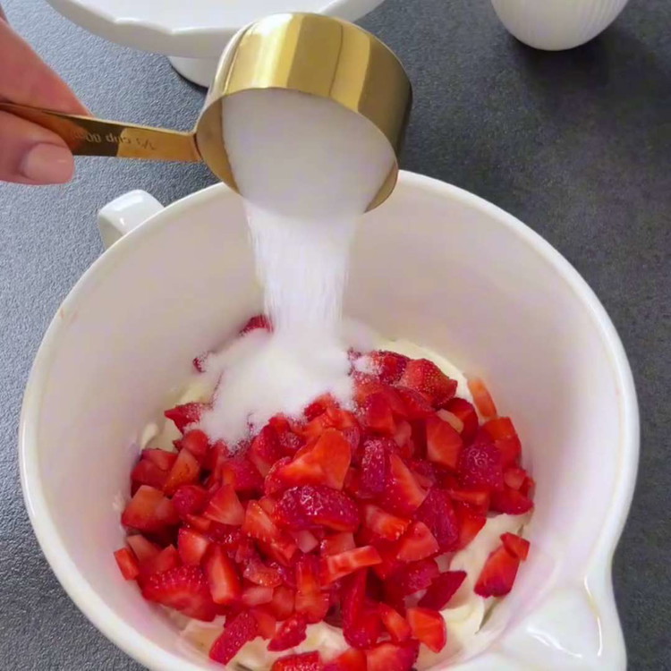 Image of Schneiden Sie die Erdbeeren in kleine Stücke und geben Sie sie in eine Schüssel. Fügen Sie den Zucker, die Speisestärke, den Quark und den Zitronensaft hinzu. Mischen Sie vorsichtig, bis die Erdbeeren gleichmäßig bedeckt sind.