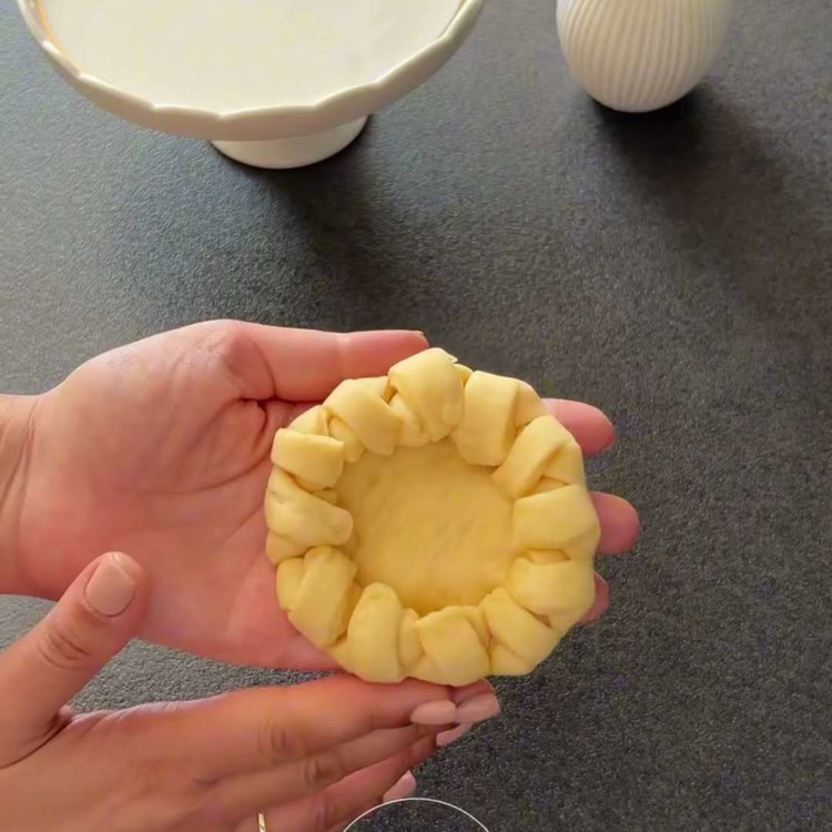 Image of Die geformten Kreise in gefettete 10 cm Backformen legen. Abdecken und weitere 30 Minuten gehen lassen. Die Schnitte vorsichtig mit den Fingern nach unten drücken.