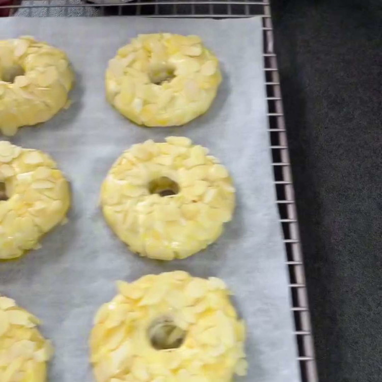 Image of Bestrijk de gewikkelde appelringen met het geklopte eigeel en bestrooi ze royaal met geschaafde amandelen.