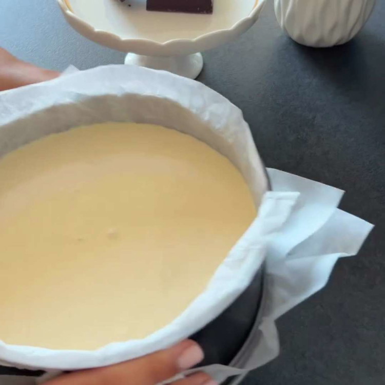 Image of Vierte la mezcla de queso en el molde preparado y golpea suavemente el molde sobre la encimera varias veces para eliminar burbujas de aire.